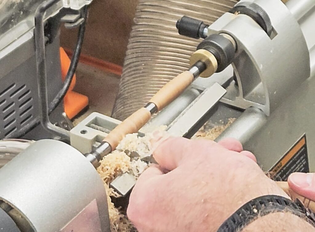 turning a pen blank on a lathe down to a pen shape using a roughing gouge