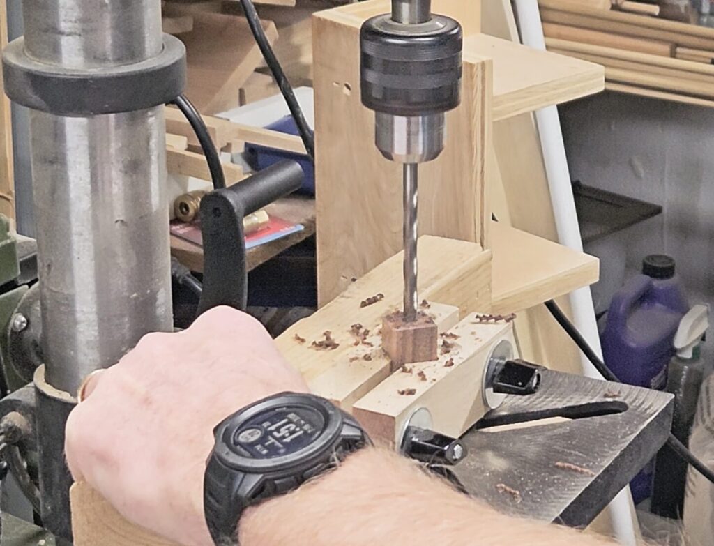 drilling a 7mm hole in the center of half the pen blank on a drill press using a vertical jig